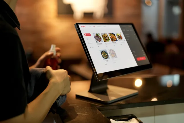 A person using a touchscreen ordering system in a modern restaurant setting. Choosing what a customer should be able to see