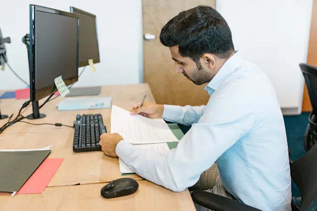 Professional man reviewing documents at his desk in a modern office setting. Designing a form around the user's task