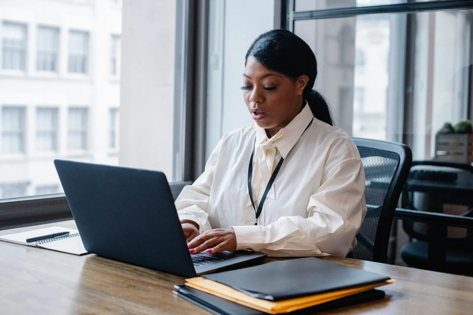 Concentrated African American female manager in white shirt working on computer during working process